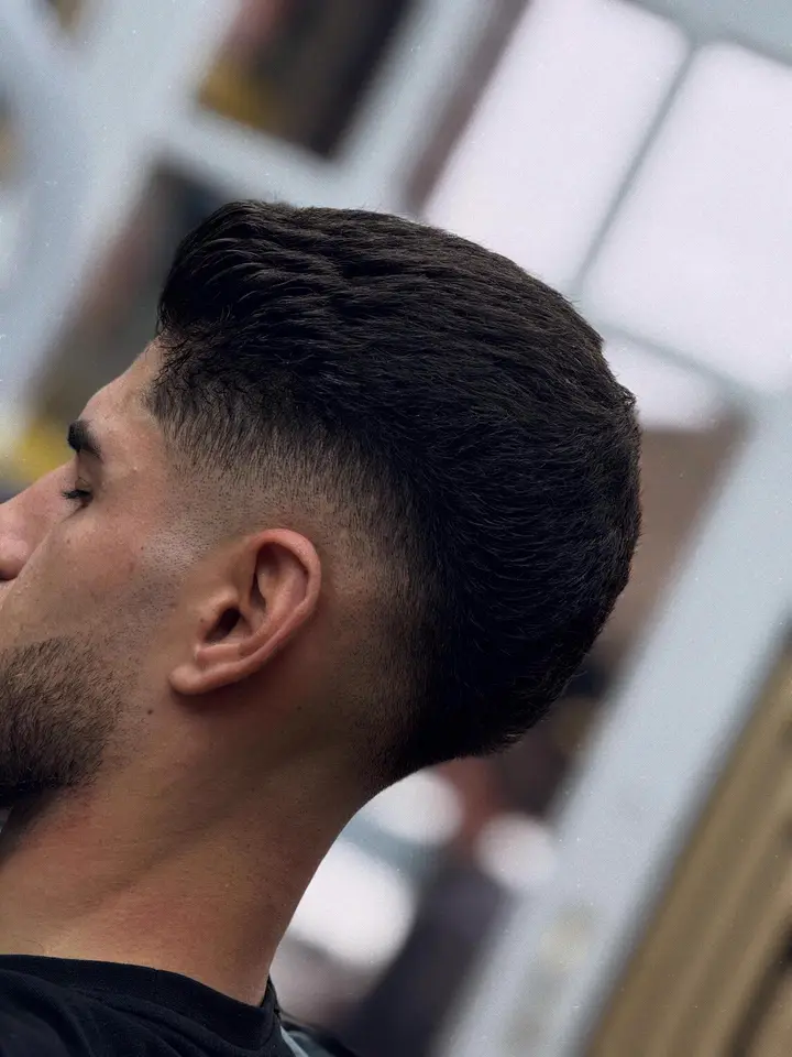 Taper fade with a textured top and sharp beard line